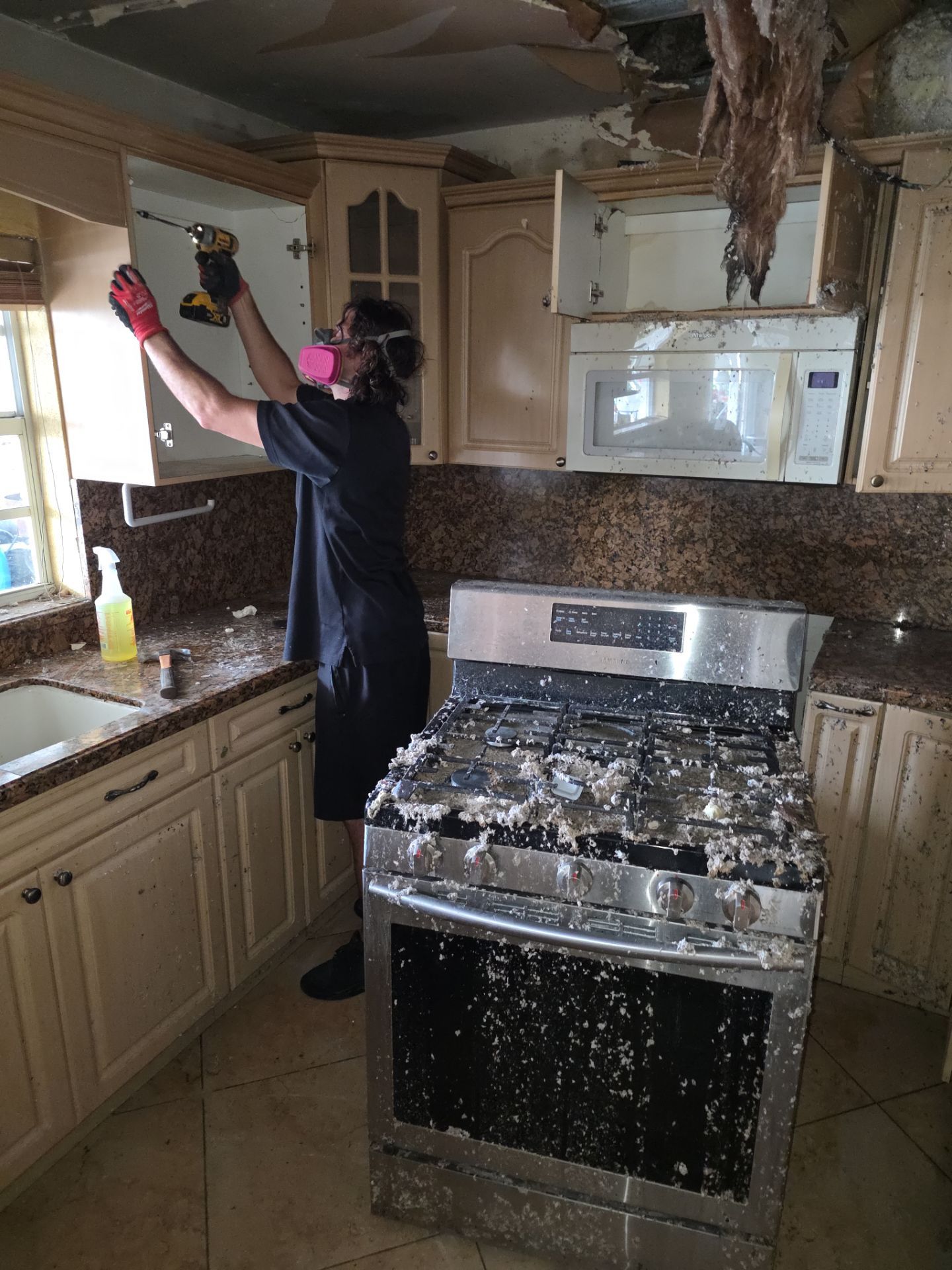 Restoration technician removing fire-damaged kitchen cabinets